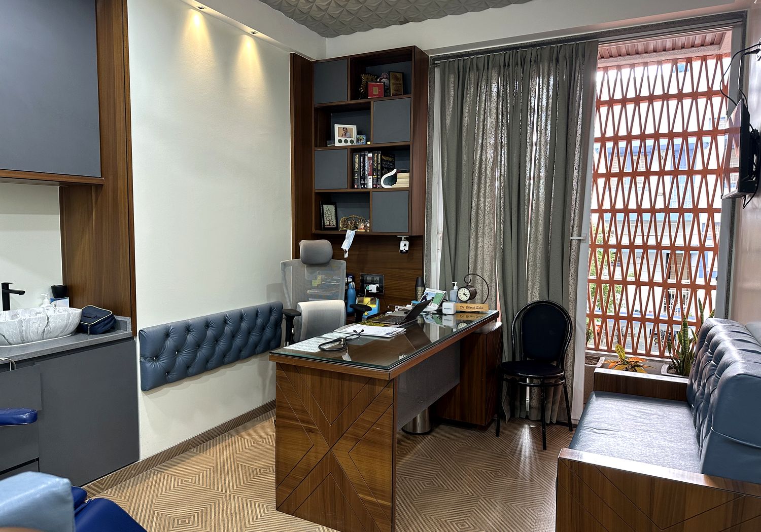 Consulting room with desk, chairs, examination couch and shelving