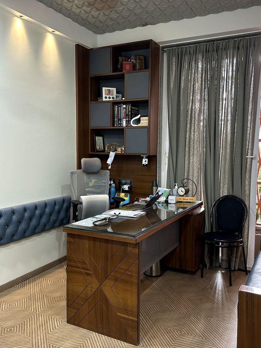 Consulting room at the clinic with a wooden desk, examination couch and bookshelf
