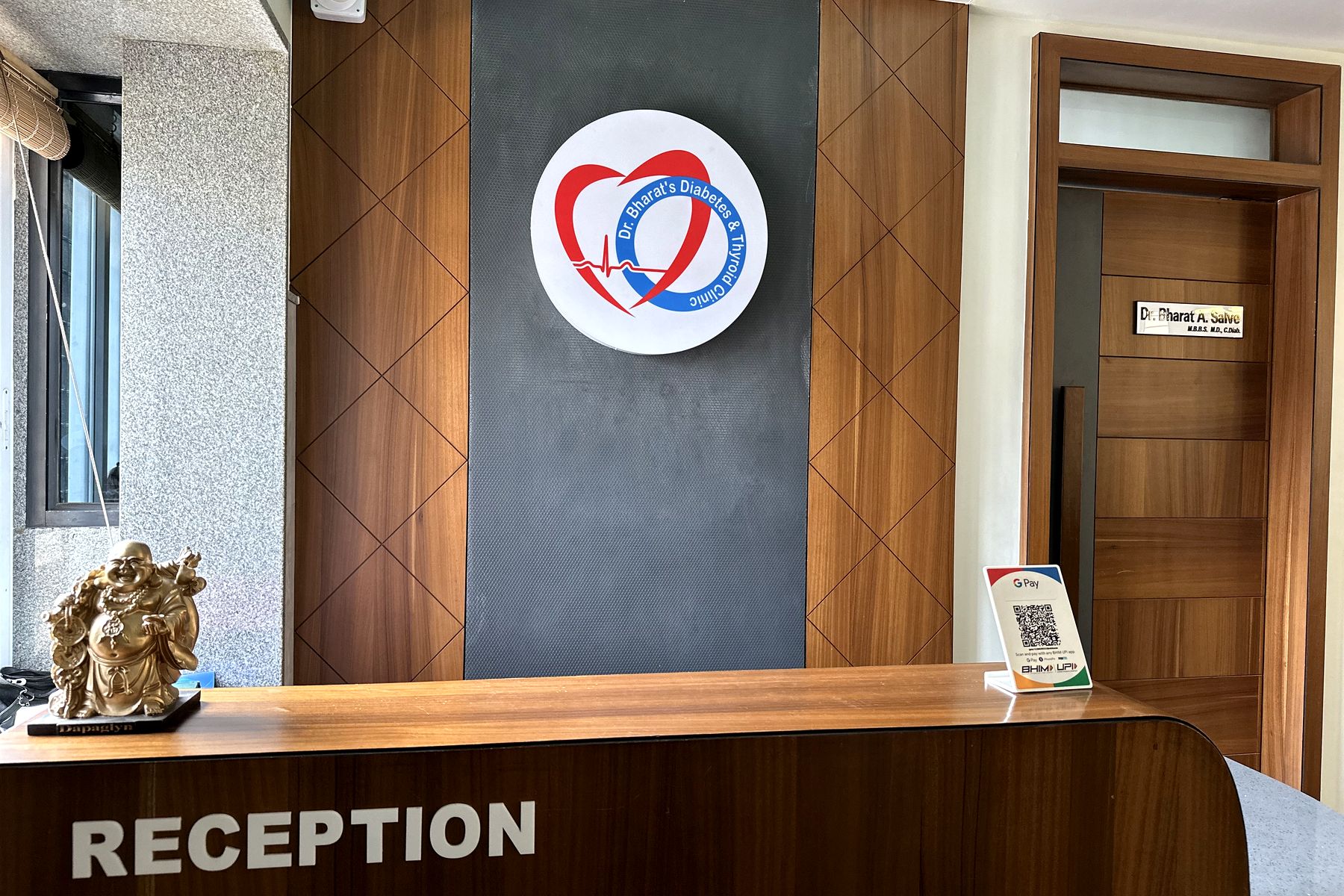 Reception of Dr. Bharat's Diabetes and Thyroid Clinic, Savedi, Ahilyanagar, with the clinic logo on a walnut panelled wall